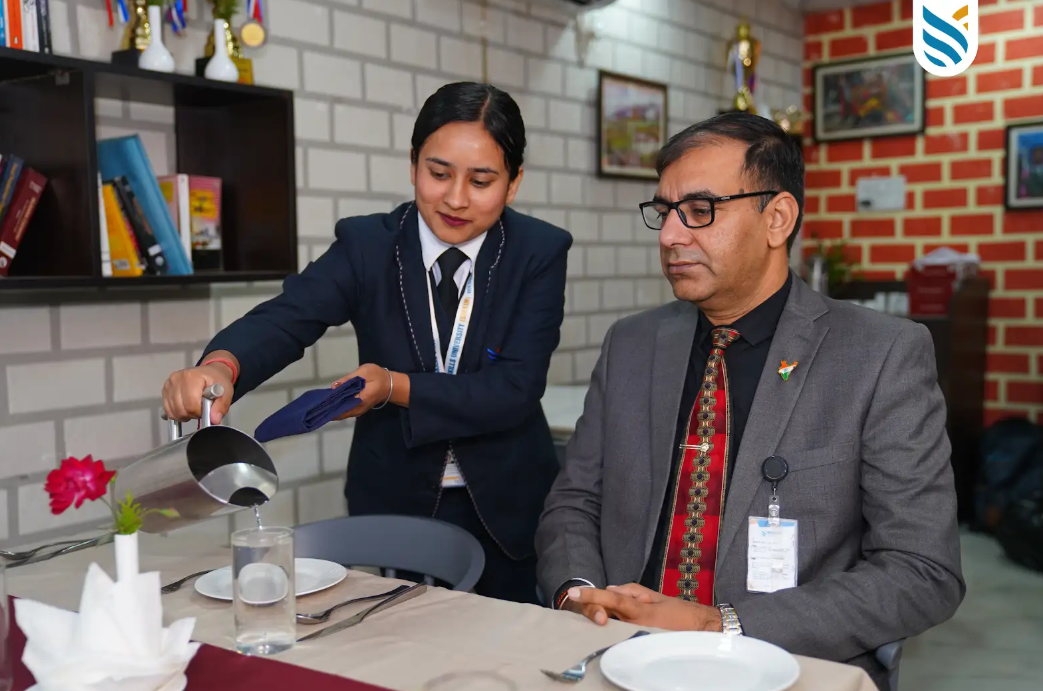 Hospitality management student demonstrating professional table service during practical restaurant training at Medhavi Skills University.