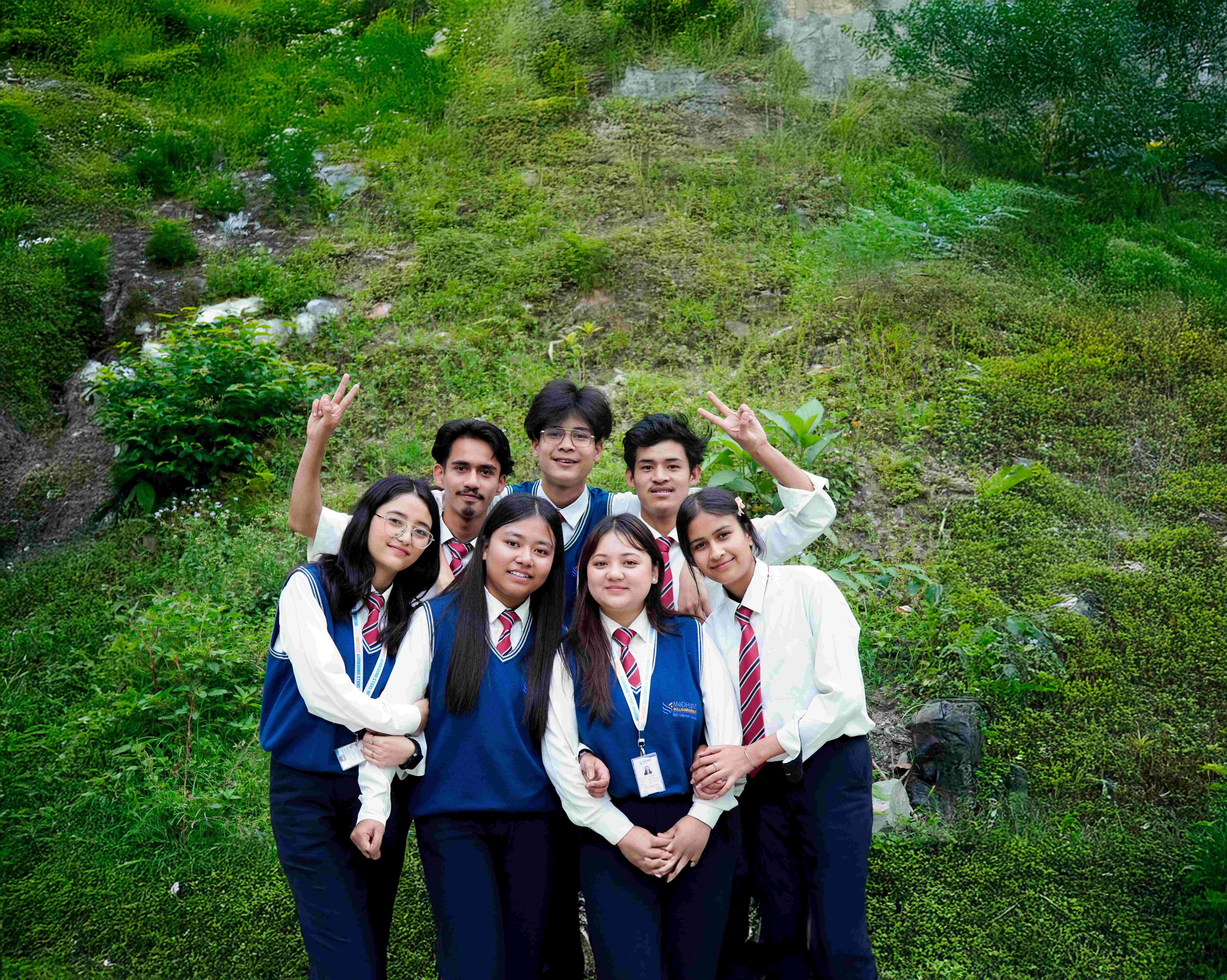 Four graduates in traditional white attire with blue stoles standing together
